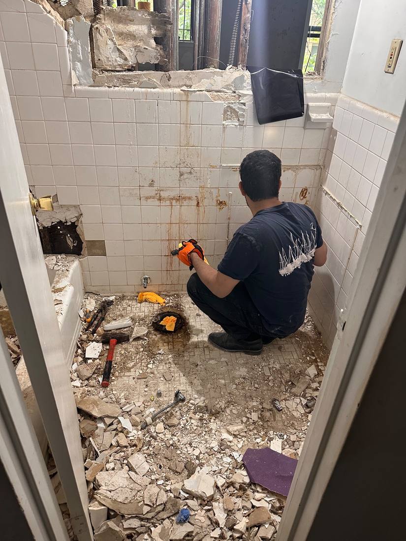Bathroom demolition: old tile and tub removed down to the plumbing