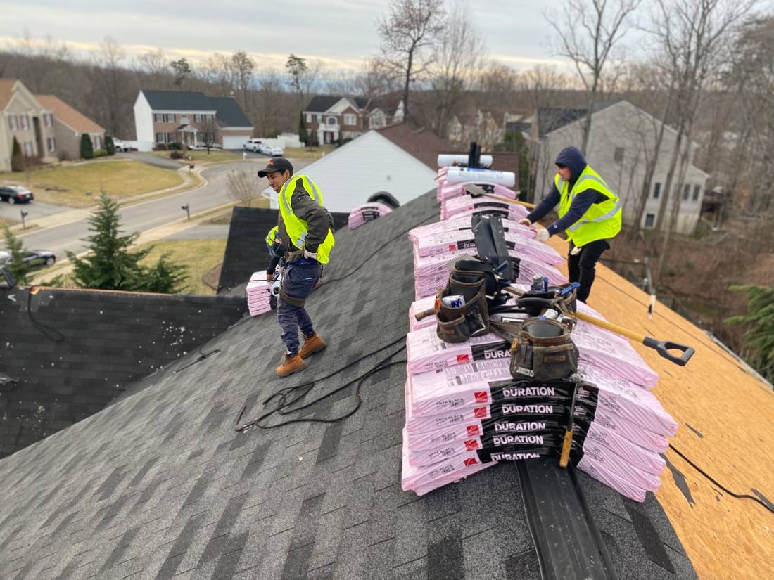 Crew staging shingles on a roof replacement